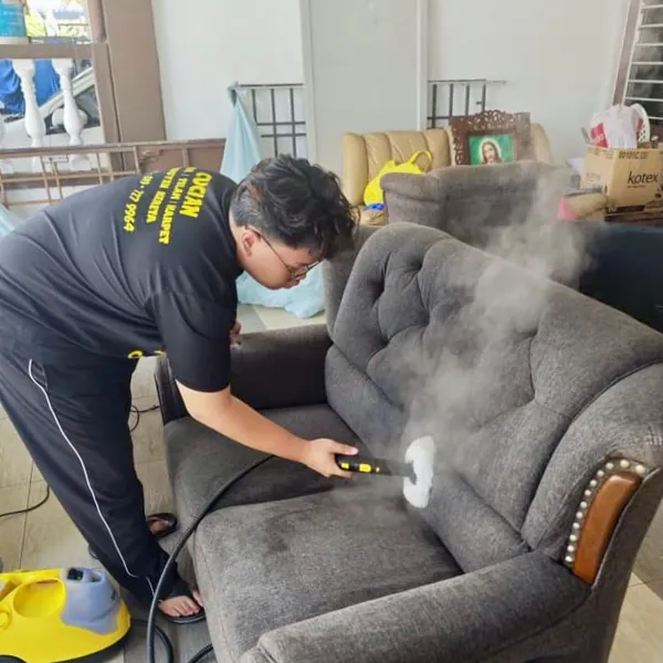 Sofa kelabu dibersihkan dengan semburan wap bertekanan