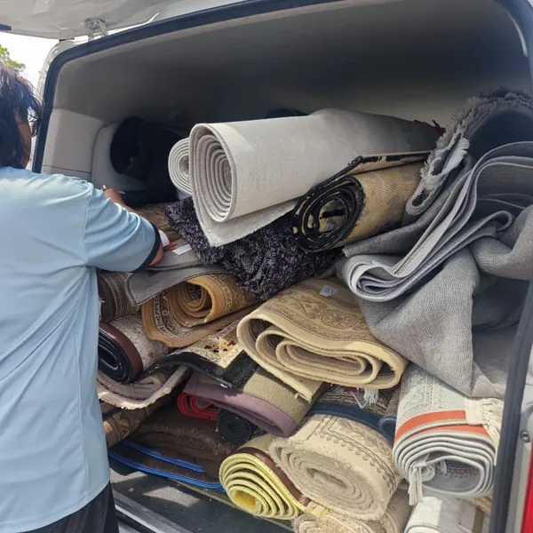 Karpet pelanggan yang telah digulung dan disusun di dalam van untuk dibawa ke kedai